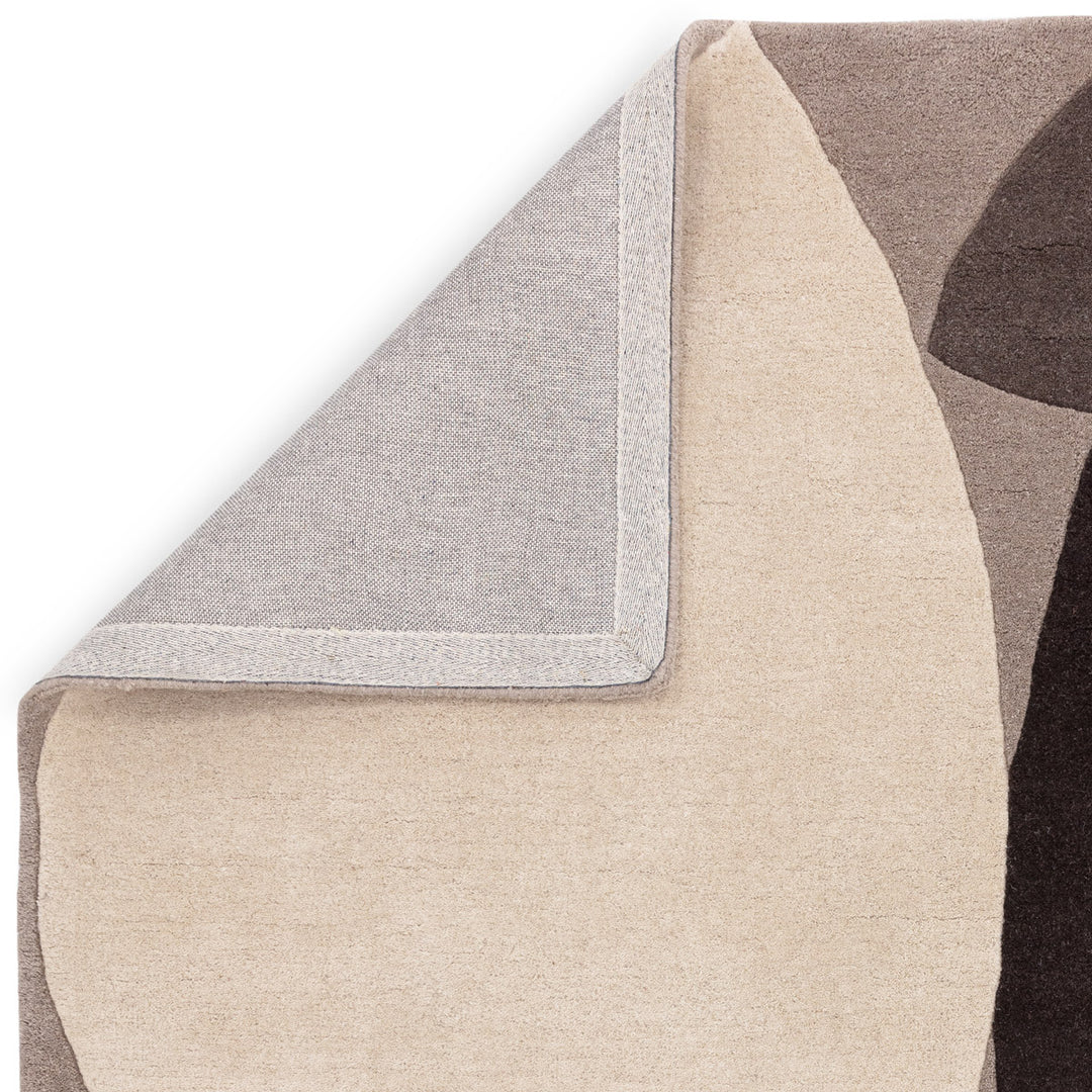 ライトグレー、アイボリー、ブラック、グレーのニュートラルカラーの自由奔放なフォルムに、まあるいバーミリオンがちょこんと映える、天然素材ウール製RUGHAUSのハンドタフテッドのモダンアートラグの素材感と裏地がわかるクロースアップ