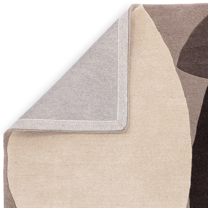 ライトグレー、アイボリー、ブラック、グレーのニュートラルカラーの自由奔放なフォルムに、まあるいバーミリオンがちょこんと映える、天然素材ウール製RUGHAUSのハンドタフテッドのモダンアートラグの素材感と裏地がわかるクロースアップ