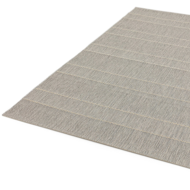200x290cmとダイニングテーブル下に敷ける大きめサイズのファッショナブルなヘリンボーンのパターンを織り込んだボーダーデザインがスタイリッシュな、ライトグレー色のインドア・アウトドア兼用RUGHAUSのシンプルモダンラグ