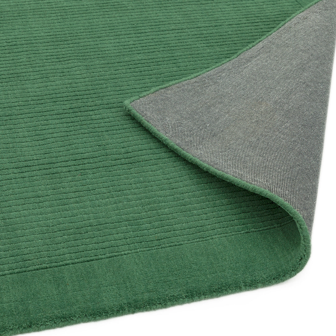 生き生きとした草葉の緑を想わせるフォレストグリーンカラーに、リブとボーダーがスタイリッシュ感を添える、サステナブルな天然素材ウール(羊毛)100%製RUGHAUSのふんわりシンプル手織りラグの素材感と裏地がわかるクロースアップ