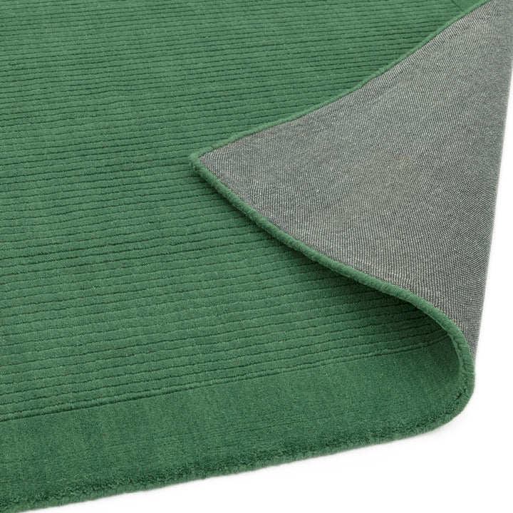 生き生きとした草葉の緑を想わせるフォレストグリーンカラーに、リブとボーダーがスタイリッシュ感を添える、サステナブルな天然素材ウール(羊毛)100%製RUGHAUSのふんわりシンプル手織りラグの素材感と裏地がわかるクロースアップ
