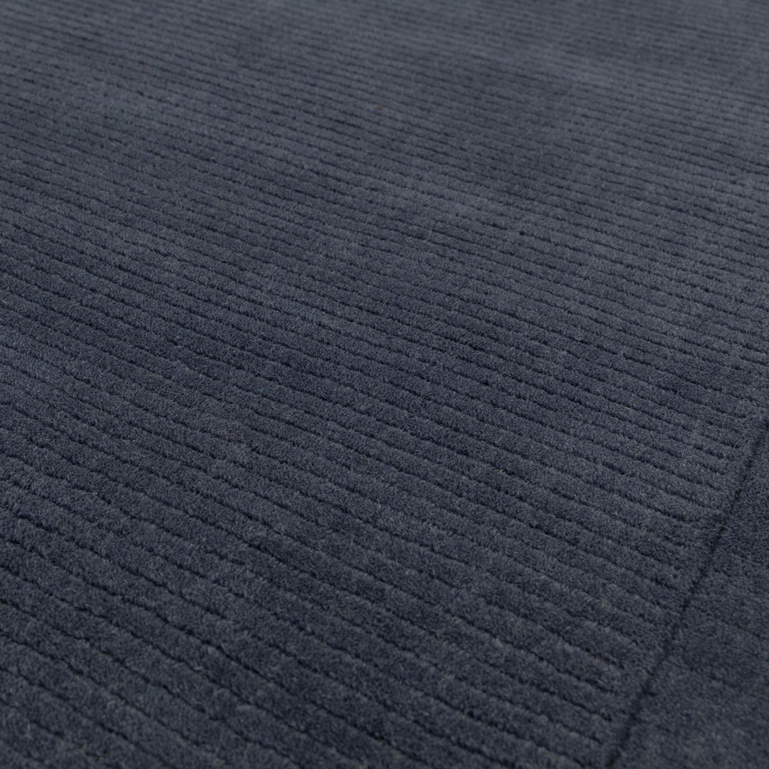 澄み切った夜空を想わせる落ち着いたネイビー色(紺色)に、リブとボーダーがスタイリッシュ感を添える、サステナブルな天然素材ウール(羊毛)100%製RUGHAUSのふんわりシンプル手織りラグの素材感がわかるクロースアップ