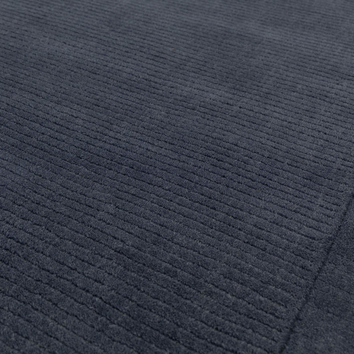 澄み切った夜空を想わせる落ち着いたネイビー色(紺色)に、リブとボーダーがスタイリッシュ感を添える、サステナブルな天然素材ウール(羊毛)100%製RUGHAUSのふんわりシンプル手織りラグの素材感がわかるクロースアップ