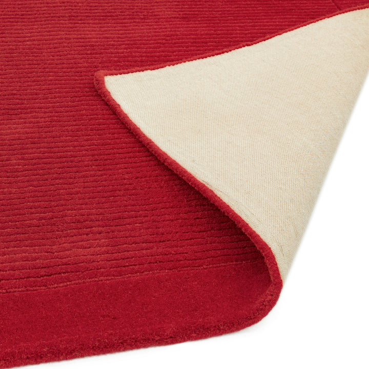 華やかな印象を与える深みのある落ち着いた赤色(ポピーレッド)の、サステナブルな天然素材ウール(羊毛)100%製RUGHAUSのふんわりシンプル手織りラグの素材感と裏地がわかるクロースアップ