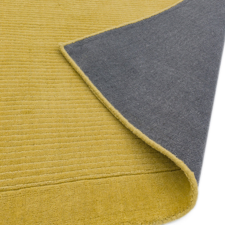オシャレ+スタイリッシュな雰囲気漂うマスタードイエロー(芥子色)の、サステナブルな天然素材ウール(羊毛)100%製RUGHAUSのふんわりシンプル手織りラグの素材感と裏地がわかるクロースアップ