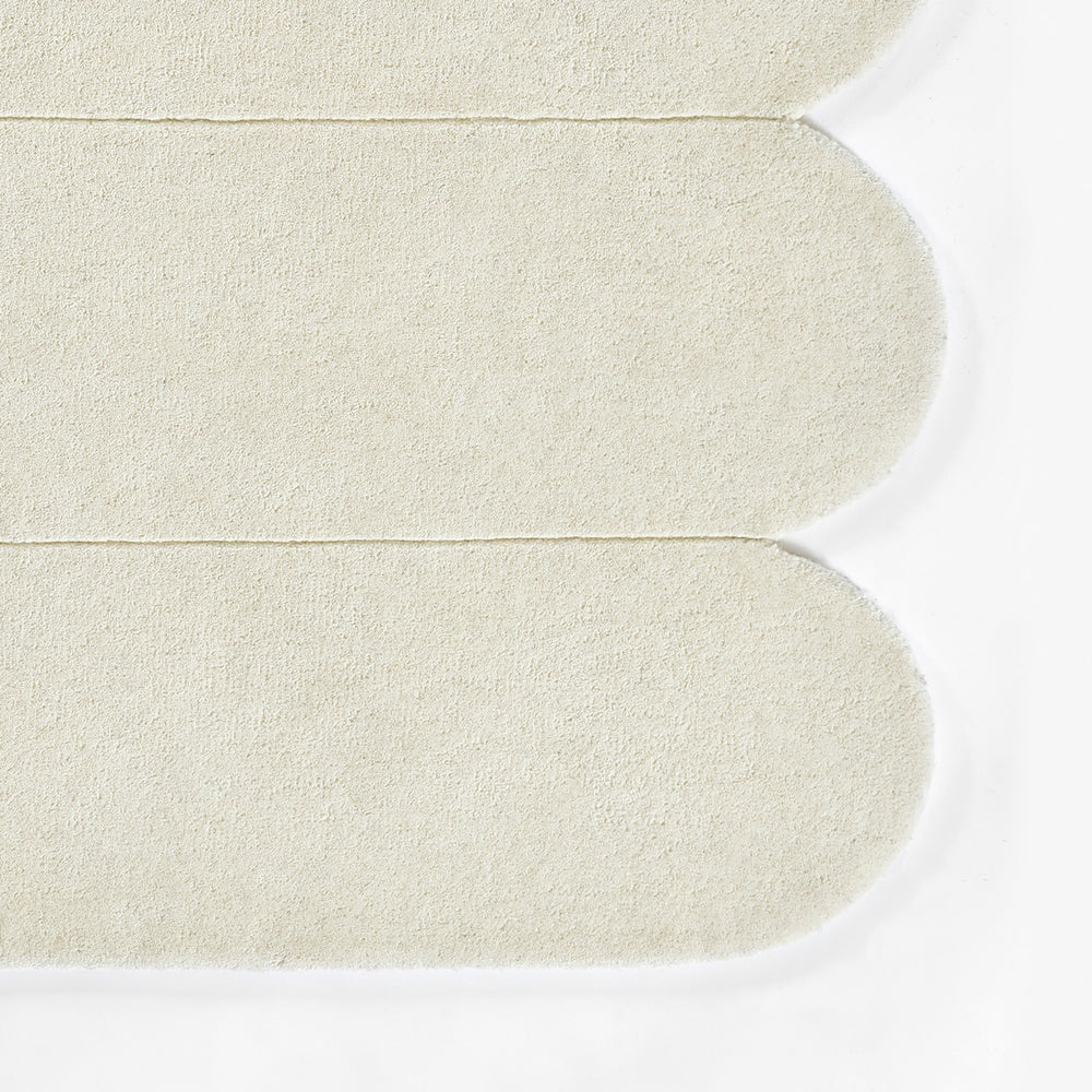 もこもことしたユニークな形が愛らしい、モダンなアート作品のような、アイボリー色のRUGHAUSの天然素材ウール100％製ハンドタフテッドラグの素材感がわかるクロースアップ
