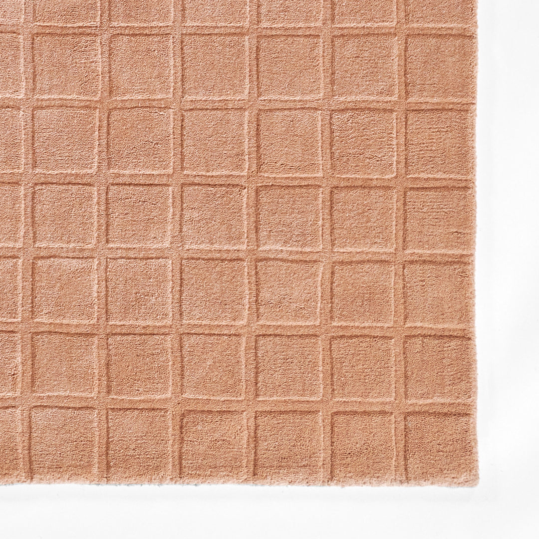 くすんだコーラルピンクのような、ニュアンスのあるアッシュローズカラー色とタイル模様が素敵な、RUGHAUSの天然素材ウール100％製手織りのエレガントモダンラグの素材感がわかるクロースアップ