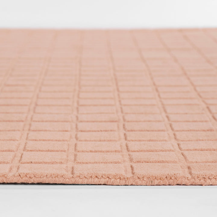 くすんだコーラルピンクのような、ニュアンスのあるアッシュローズカラー色とタイル模様が素敵な、RUGHAUSの天然素材ウール100％製手織りのエレガントモダンラグの素材感がわかるクロースアップ