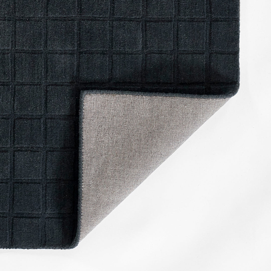 ミッドナイトブルーのように深く落ち着いた色合いのネイビーカラーとタイル模様が素敵な、RUGHAUSの天然素材ウール100％製手織りのエレガントモダンラグの素材感がわかるクロースアップ