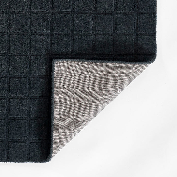 ミッドナイトブルーのように深く落ち着いた色合いのネイビーカラーとタイル模様が素敵な、RUGHAUSの天然素材ウール100％製手織りのエレガントモダンラグの素材感がわかるクロースアップ