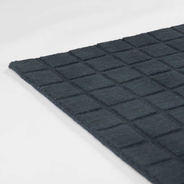 ミッドナイトブルーのように深く落ち着いた色合いのネイビーカラーとタイル模様が素敵な、RUGHAUSの天然素材ウール100％製手織りのエレガントモダンラグの素材感がわかるクロースアップ