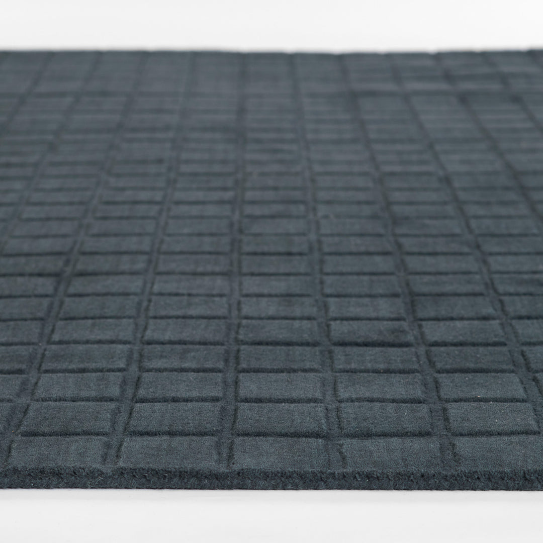 ミッドナイトブルーのように深く落ち着いた色合いのネイビーカラーとタイル模様が素敵な、RUGHAUSの天然素材ウール100％製手織りのエレガントモダンラグの素材感がわかるクロースアップ