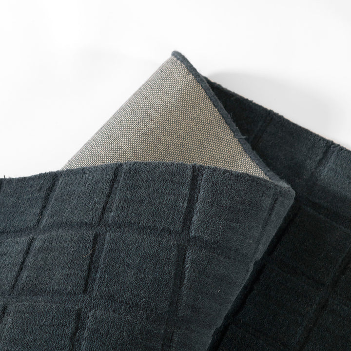 ミッドナイトブルーのように深く落ち着いた色合いのネイビーカラーとタイル模様が素敵な、RUGHAUSの天然素材ウール100％製手織りのエレガントモダンラグの素材感がわかるクロースアップ