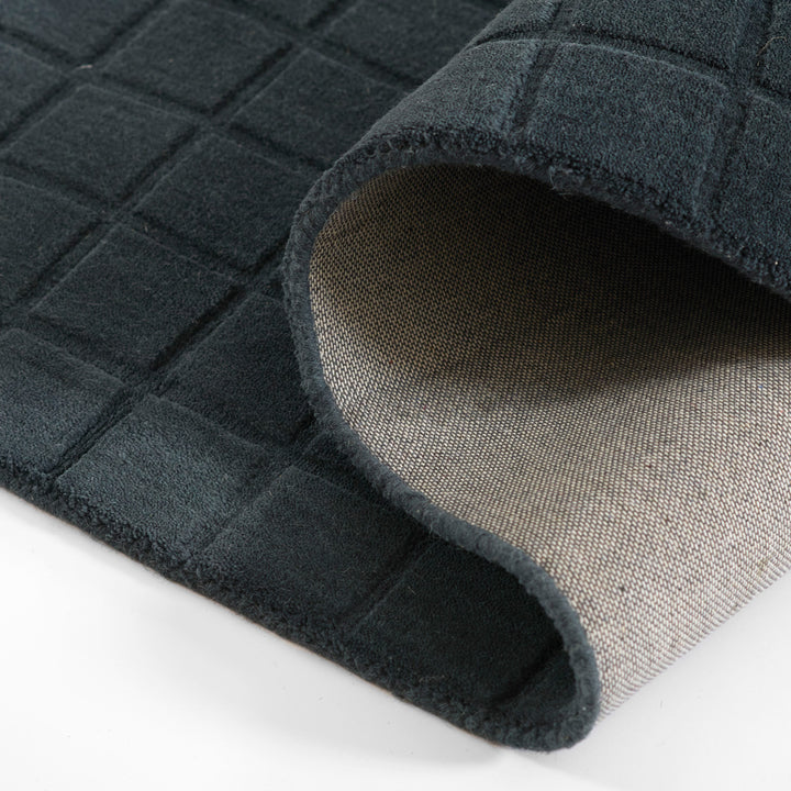 ミッドナイトブルーのように深く落ち着いた色合いのネイビーカラーとタイル模様が素敵な、RUGHAUSの天然素材ウール100％製手織りのエレガントモダンラグの素材感がわかるクロースアップ