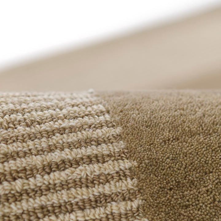 ベージュ、トープ、ブラウンベージュのアーシーなカラーパレットが大胆なボーダーの構図でキリリとハーモニーを奏でる、RUGHAUSの天然素材ウール製ハンドタフト・手織りの上質ナチュラルラグの素材感がわかるクロースアップ