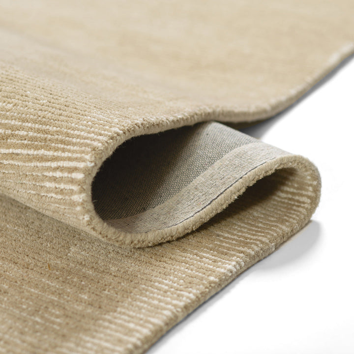 温かな印象のベージュ、オートミール、トープのカラーパレットに、幅細のリブがスタイリッシュに映えた、RUGHAUSの天然素材ウール製ハンドタフト・手織りの上質ナチュラルラグの素材感と裏地がわかるクロースアップ