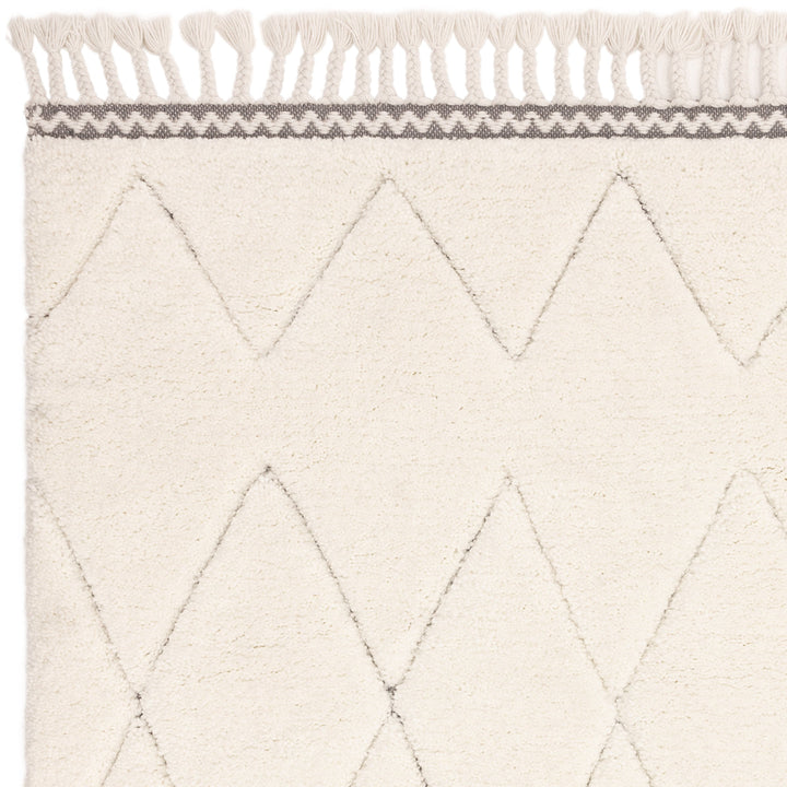 伝統的なベルベルキリムのテクスチャーやデザインにインスパイアされて織り上げた、ダイヤ模様がチャーミングな、ふわふわとした柔らかなマイクロファイバーポリエステル製RUGHAUSのベージュ・アイボリー色のベニワレンスタイルモロッカンシャギーラグの素材感がわかるクロースアップ