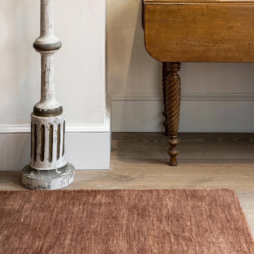 アブラッシュ効果と呼ばれるテクニックでできた、手織りならではの味わい深いコッパーブラウンのグラデーションが魅力的な、RUGHAUSの天然素材ウール製手織りの上質ナチュラルラグを主役にしたシックモダンなリビングルーム