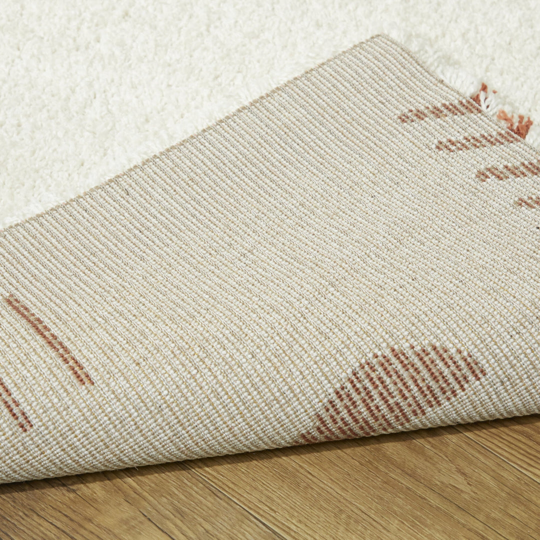 ふわふわとした手触りと厚み、アイボリー×テラコッタ色の素朴でアーティスティックなパターンが魅力的なコンテンポラリーモダンラグの素材感と裏地がわかるクロースアップ
