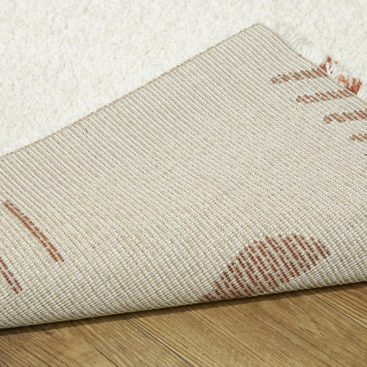 ふわふわとした手触りと厚み、アイボリー×テラコッタ色の素朴でアーティスティックなパターンが魅力的なコンテンポラリーモダンラグの素材感と裏地がわかるクロースアップ