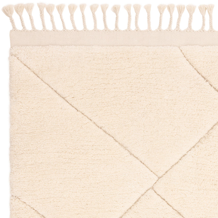 伝統的なベルベルキリムのテクスチャーやデザインにインスパイアされて織り上げた、ふわふわとした柔らかなマイクロファイバーポリエステル製RUGHAUSのベージュ・アイボリー色のベニワレンスタイルモロッカンラグの素材感がわかるクロースアップ