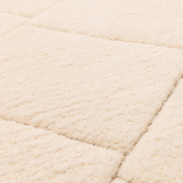 伝統的なベルベルキリムのテクスチャーやデザインにインスパイアされて織り上げた、ふわふわとした柔らかなマイクロファイバーポリエステル製RUGHAUSのベージュ・アイボリー色のベニワレンスタイルモロッカンラグの素材感がわかるクロースアップ