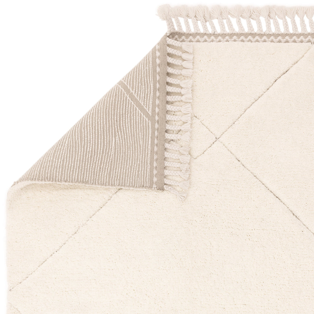 伝統的なベルベルキリムのテクスチャーやデザインにインスパイアされて織り上げた、ふわふわとした柔らかなマイクロファイバーポリエステル製RUGHAUSのベージュ・アイボリー色のベニワレンスタイルモロッカンラグの素材感と裏面がわかるクロースアップ