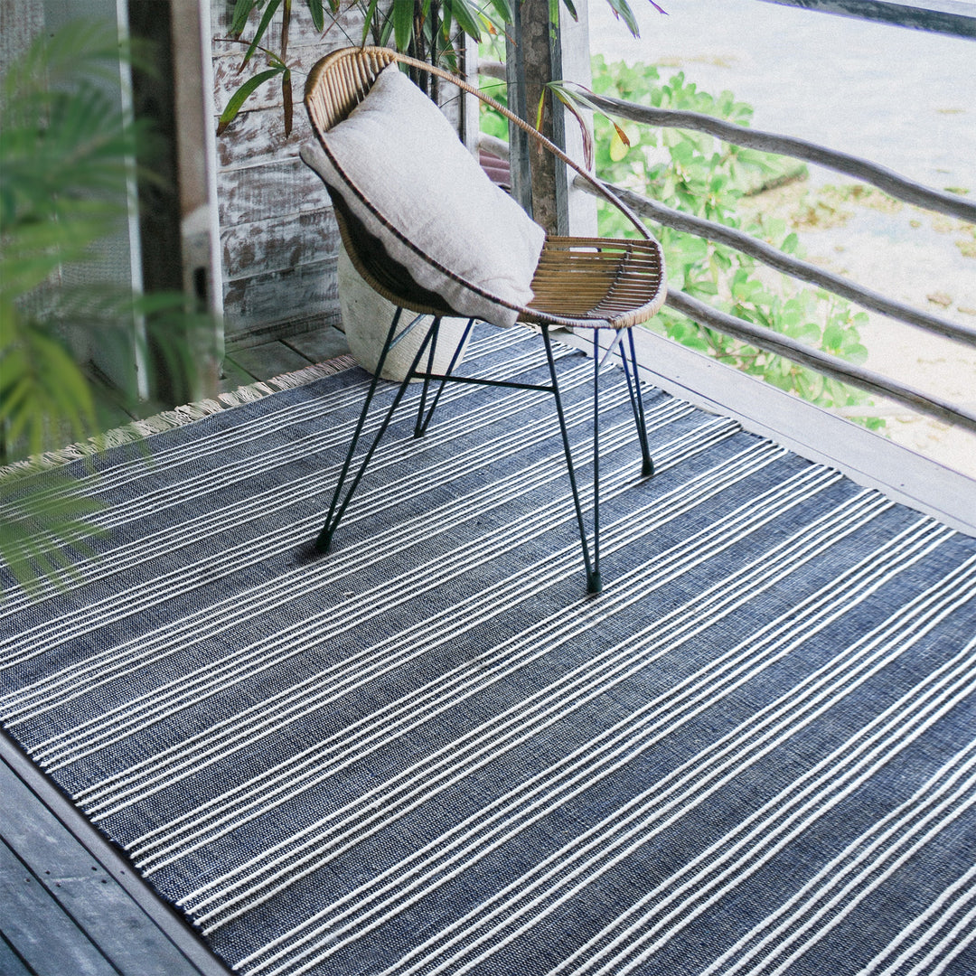 南仏リゾート気分を味わえる爽やかなブルー × アイボリーのストライプがスタイリッシュなRUGHAUSの再生ポリエステル製手織りナチュラルラグを主役にテラスやバルコニーでアウトドアリビングを楽しむイメージ