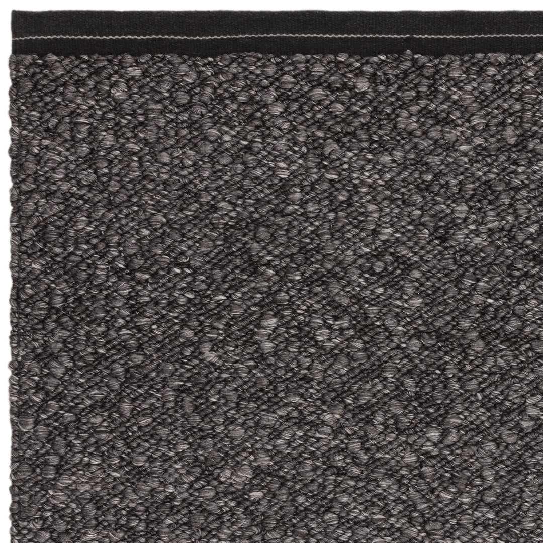 シックなチャコールグレーの色合いと、ブークレ（Boucle）織りのざっくりとした風合いがパーフェクトにマッチした、RUGHAUSの手織りのシンプルモダンラグの素材感がわかるクロースアップ