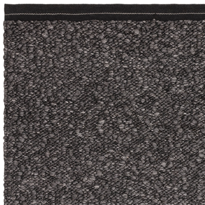 シックなチャコールグレーの色合いと、ブークレ（Boucle）織りのざっくりとした風合いがパーフェクトにマッチした、RUGHAUSの手織りのシンプルモダンラグの素材感がわかるクロースアップ