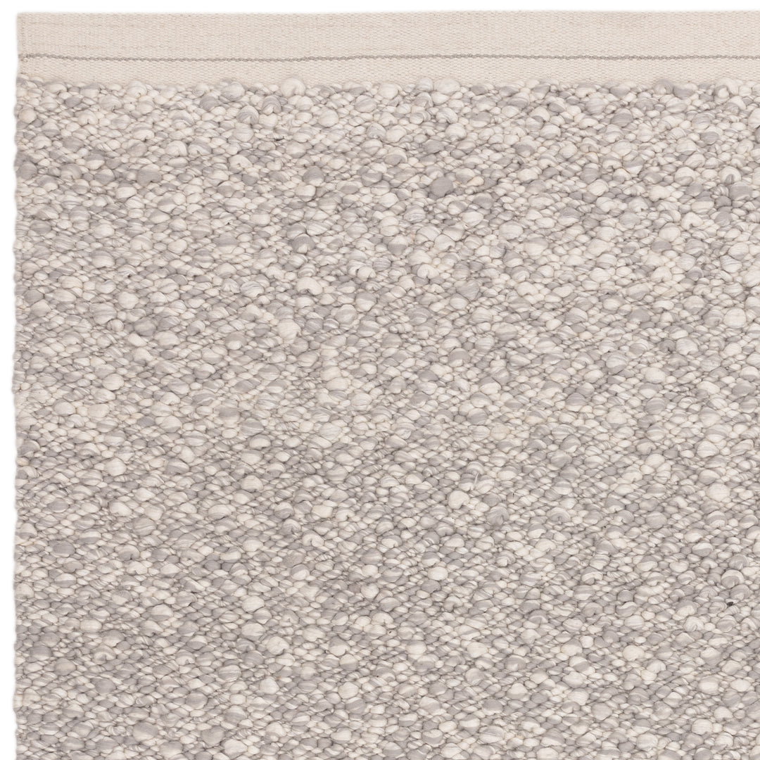 洗練されたライトグレーの色合いと、ブークレ（Boucle）織りのざっくりとした風合いがパーフェクトにマッチした、RUGHAUSの手織りのシンプルモダンラグの素材感がわかるクロースアップ