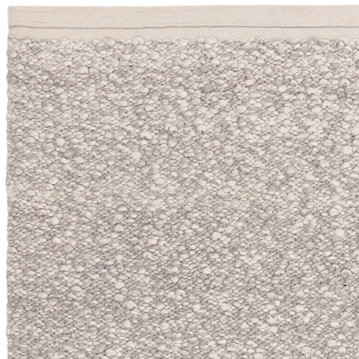 洗練されたライトグレーの色合いと、ブークレ（Boucle）織りのざっくりとした風合いがパーフェクトにマッチした、RUGHAUSの手織りのシンプルモダンラグの素材感がわかるクロースアップ