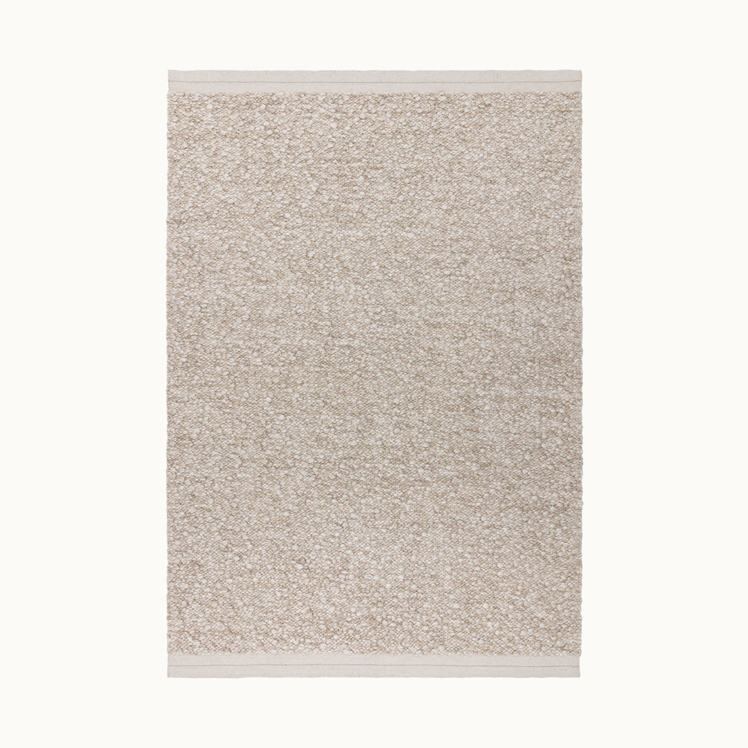160x230cmサイズの羊毛そのままのようなベージュの暖かな色合いと、ブークレ（Boucle）織りのざっくりとした風合いがパーフェクトにマッチした、RUGHAUSの手織りのシンプルモダンラグ