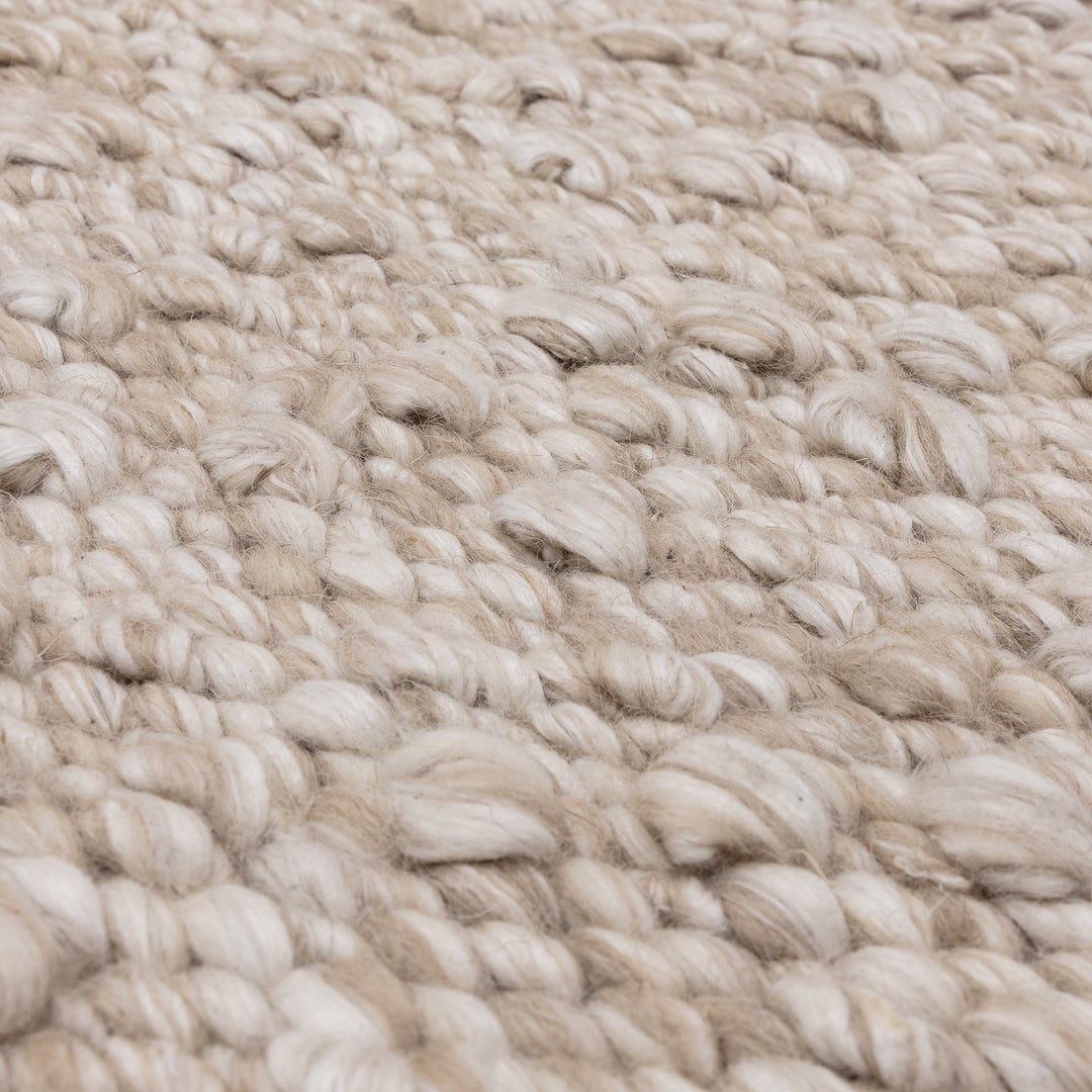 羊毛そのままのようなベージュの暖かな色合いと、ブークレ（Boucle）織りのざっくりとした風合いがパーフェクトにマッチした、RUGHAUSの手織りのシンプルモダンラグの素材感がわかるクロースアップ