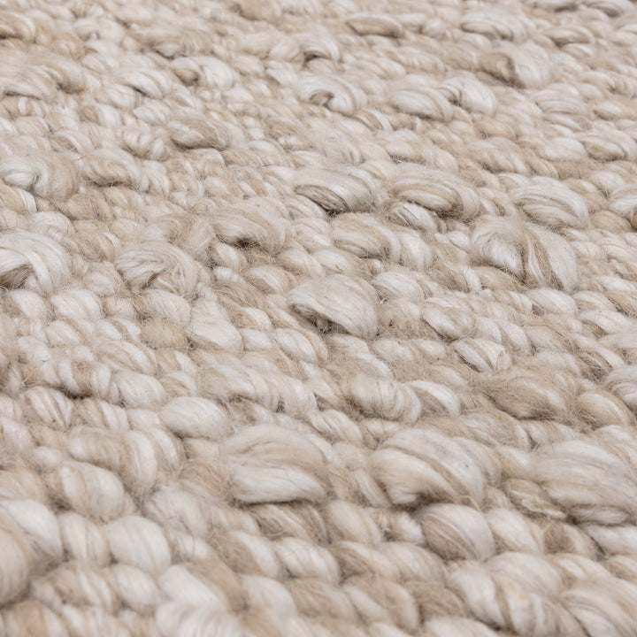 羊毛そのままのようなベージュの暖かな色合いと、ブークレ（Boucle）織りのざっくりとした風合いがパーフェクトにマッチした、RUGHAUSの手織りのシンプルモダンラグの素材感がわかるクロースアップ